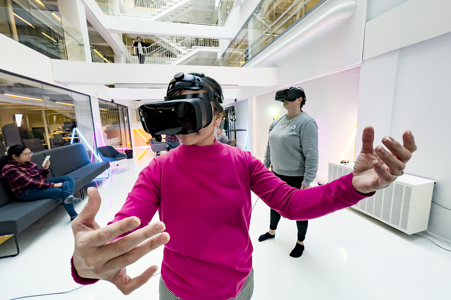 Woman wearing a pink shirt is testing a VR headset.