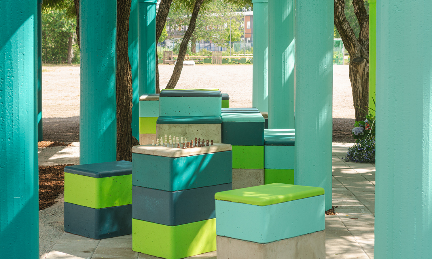 Blue and green toned concrete cubes under a pergola structure with the same colour scheme