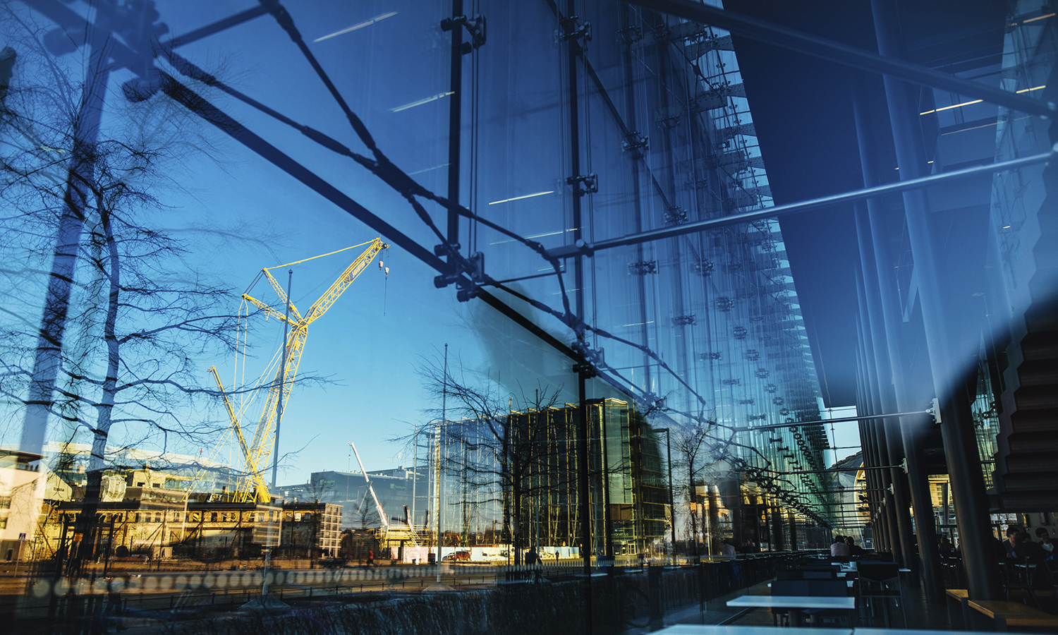 A construction site and blue skies reflected on a glass wall of a building