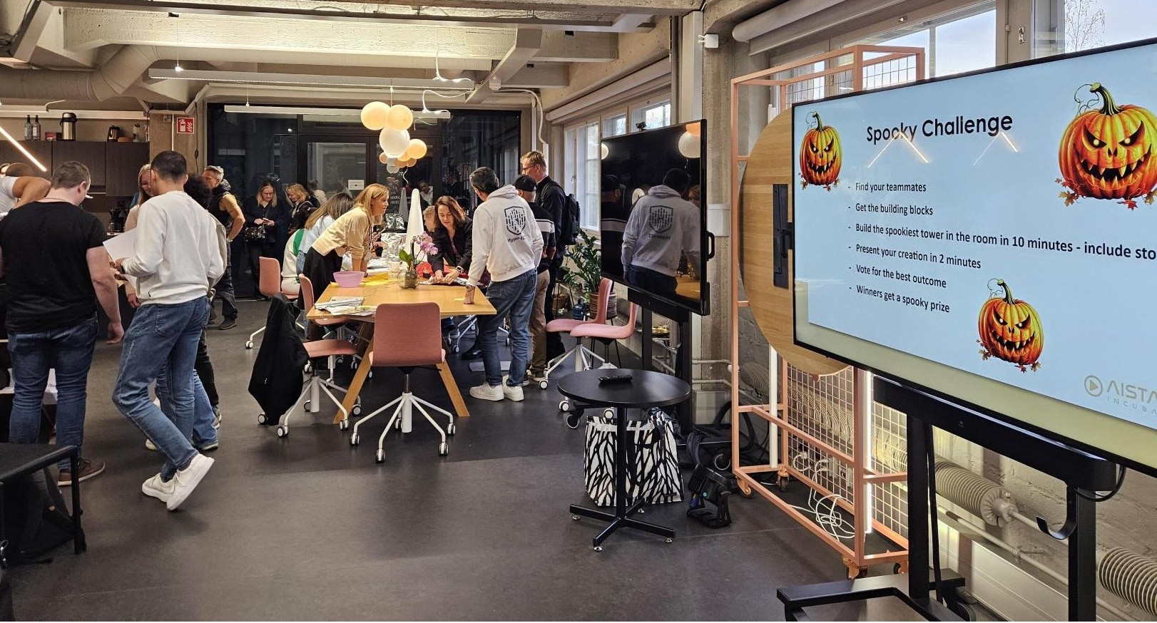 Men and women in a workshop, talking arond a table. A screen in the front.