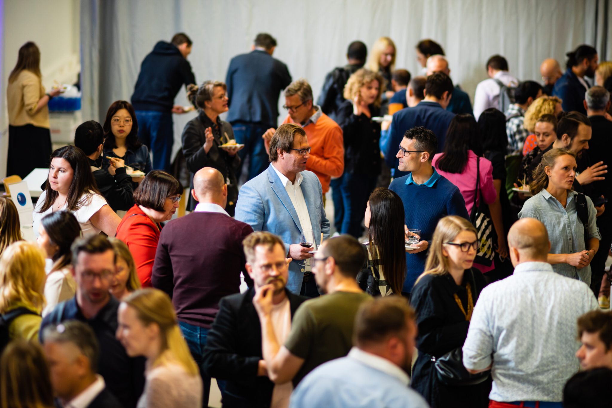 Kymmeniä ihmisiä keskustelemassa ja verkostoitumassa keskenään tapahtumassa.