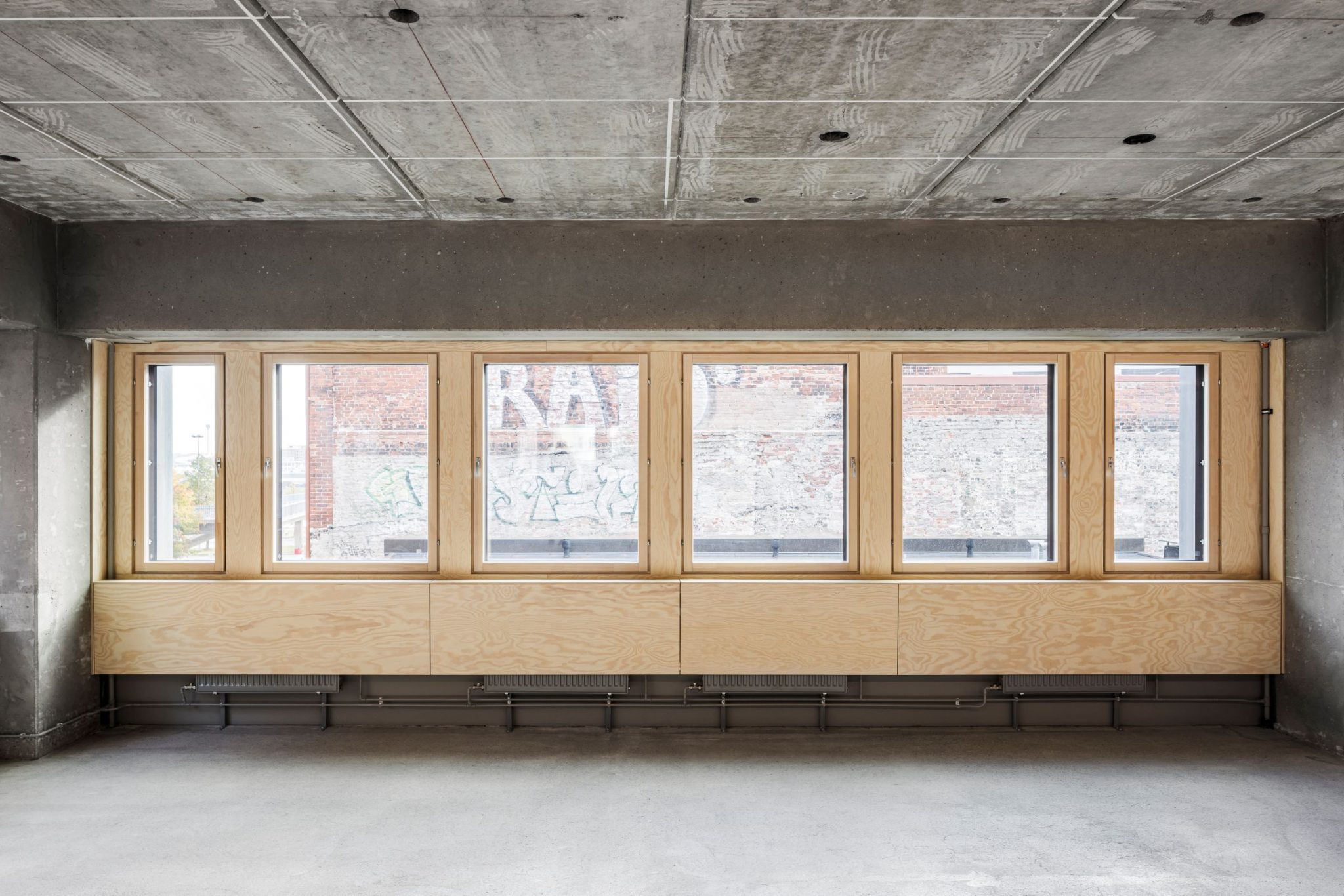 Rivissä ikkunoita, sisätilasta käsin kuvattu. Läpi näkyy graffiteja vastapäätä.